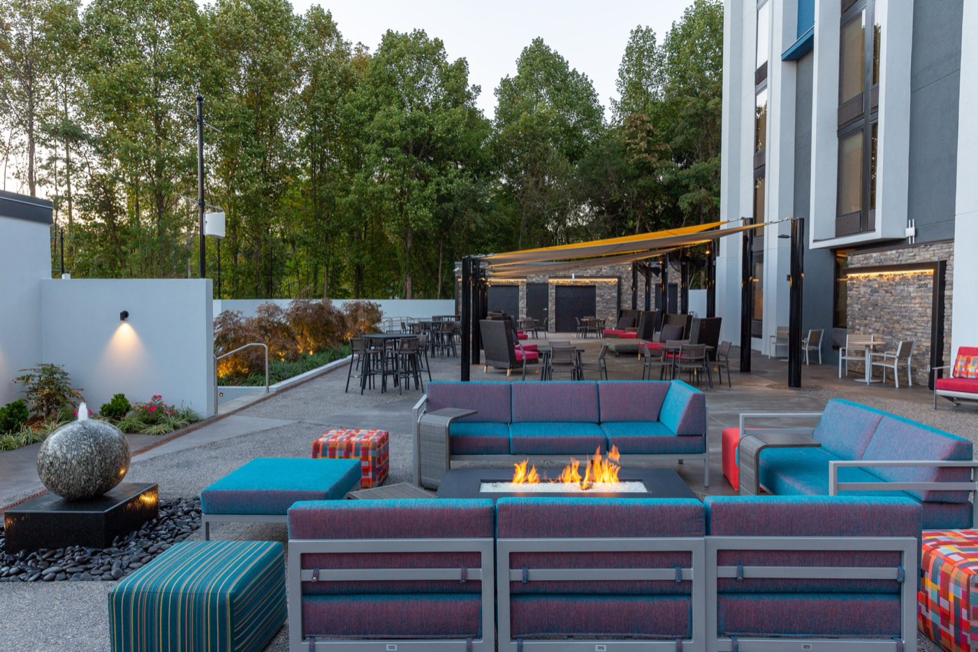 The renovated outdoor patio at Hilton Garden Inn Asheville South, one of our five hotels, with a fire pit and lounge seating at dusk